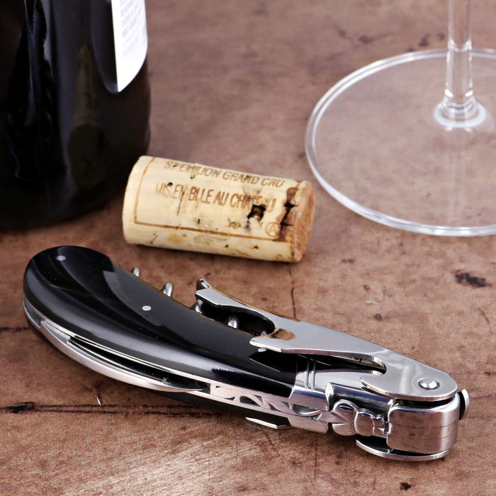 Laguiole Magnum Black Horn Tip Corkscrew, close-up side view, with a wine bottle and cork.