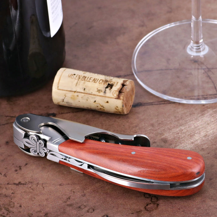 Laguiole Magnum Corkscrew, rosewood handle with Deco Fleur de Lys, beside a cork and wine glass.